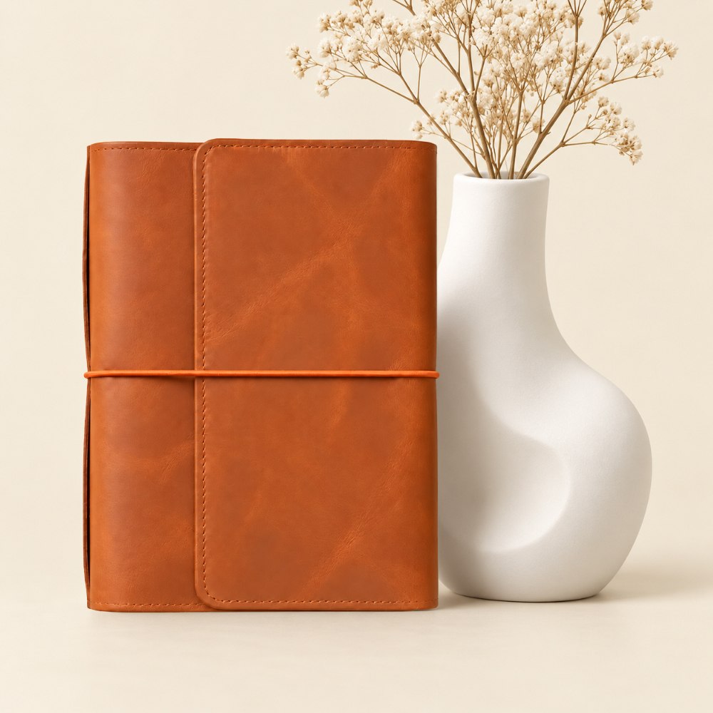 Handmade orange leather journal cover featuring six elastic bands and multiple inner pockets.