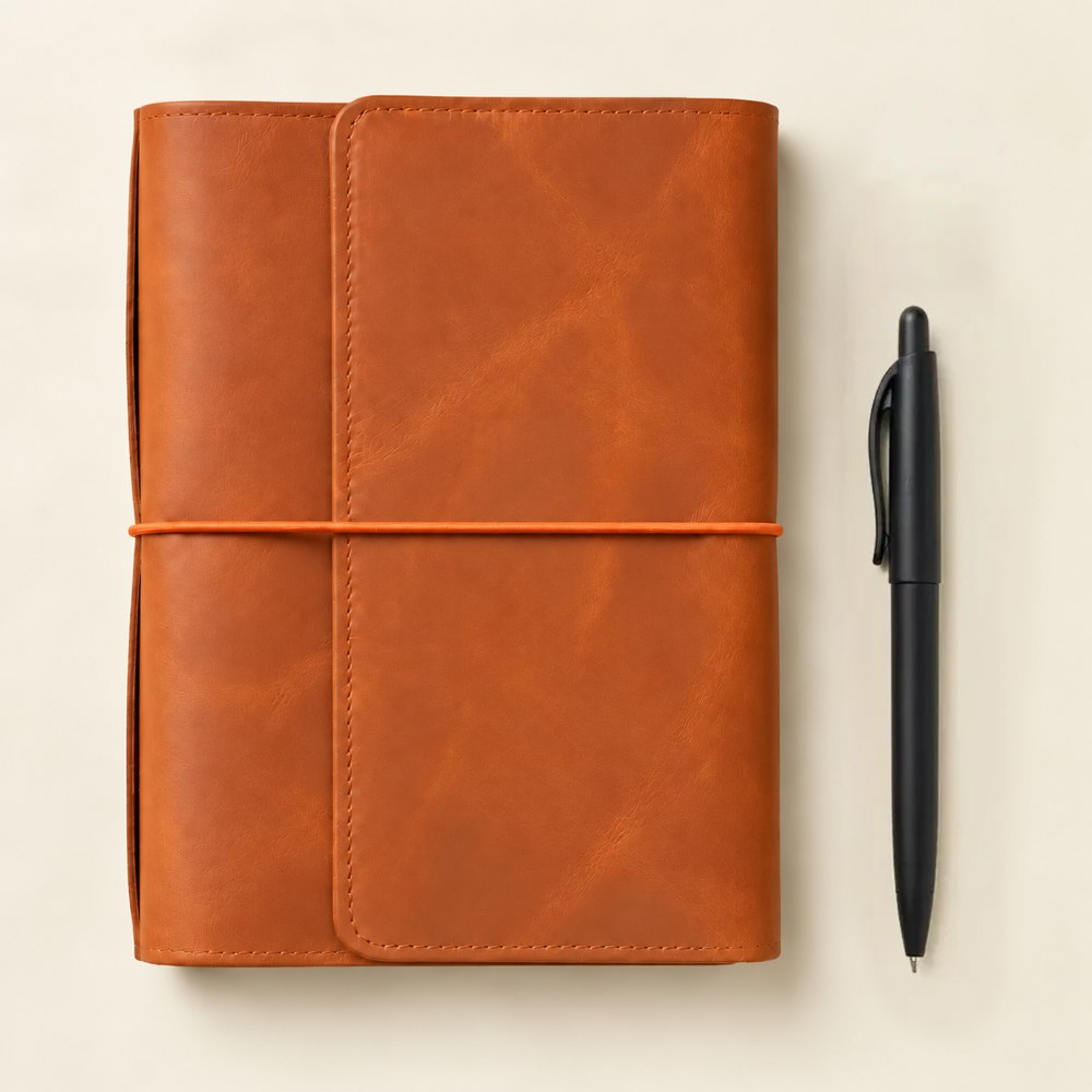 Stylish orange leather notebook cover with six elastic bands and several convenient interior pockets.