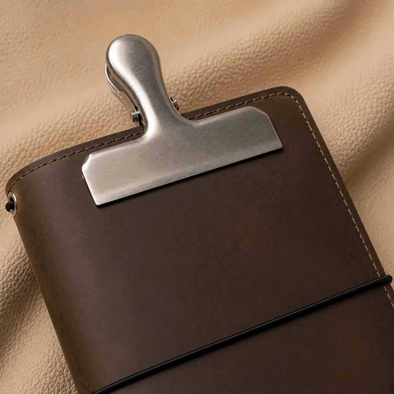 Silver metal bookmark clip attached to a leather notebook for quick and easy page marking.