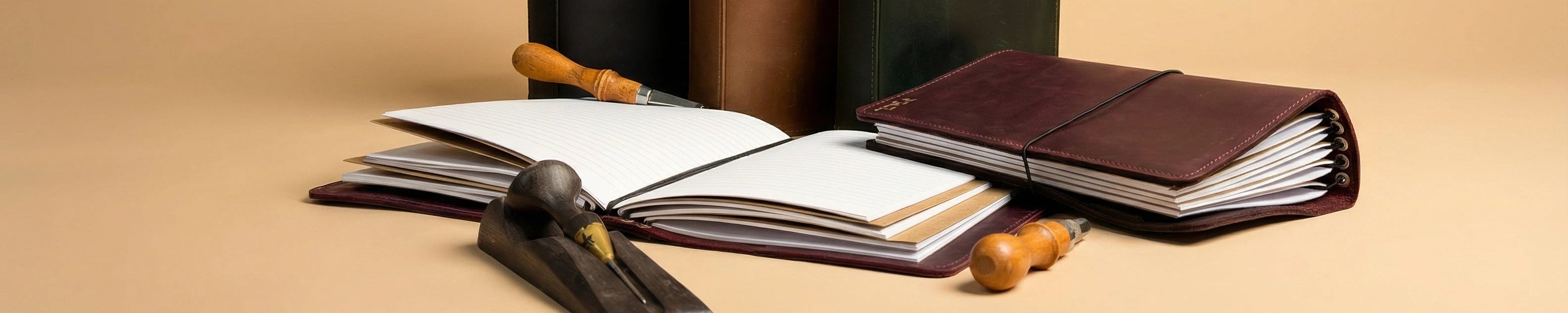 Collection of leather-bound books and writing instruments on a beige background