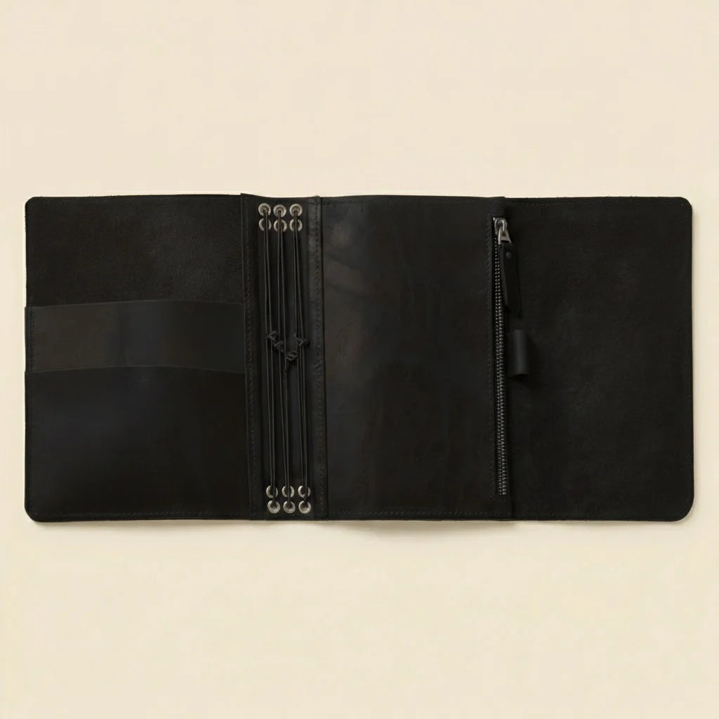 Black leather notebook and pen on a beige background