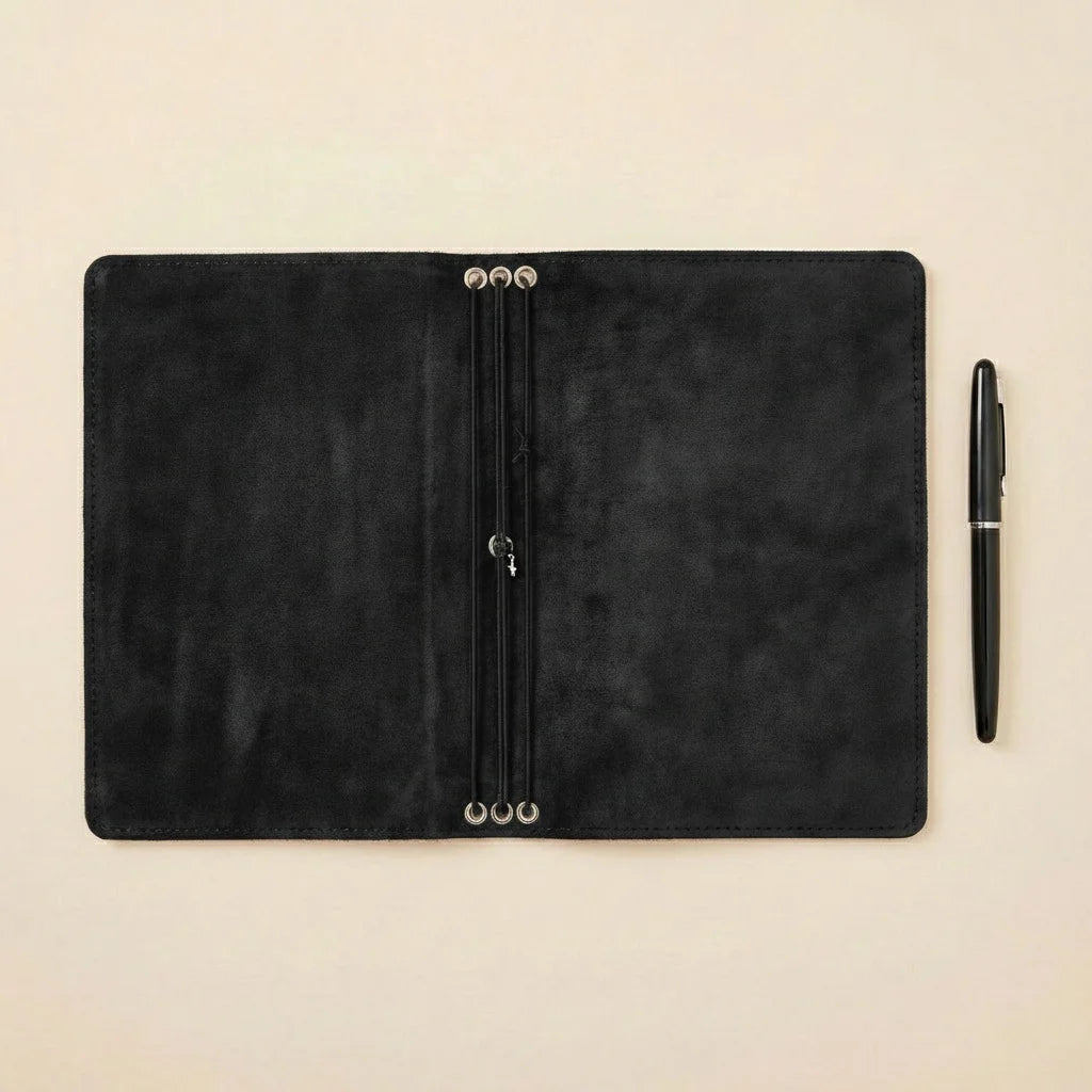 Black leather planner with a pen on a beige background