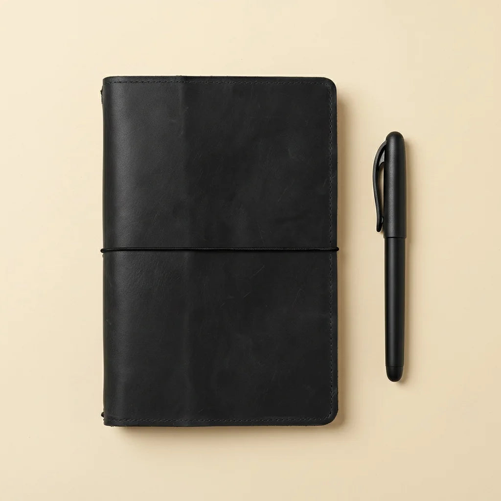 Black leather notebook and pen on a beige background