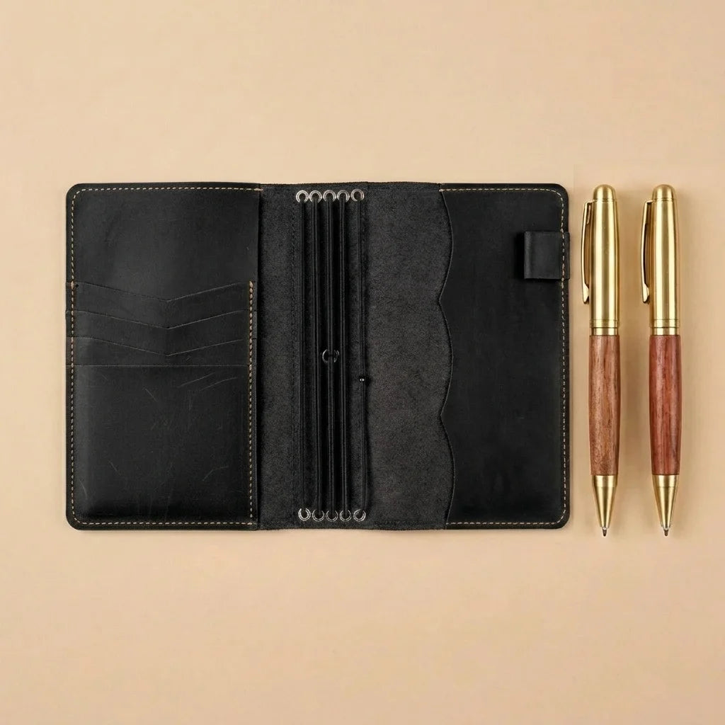 Black leather organizer with two pens on a beige background