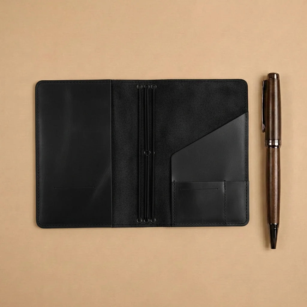 Black leather notebook with a pen on a beige background