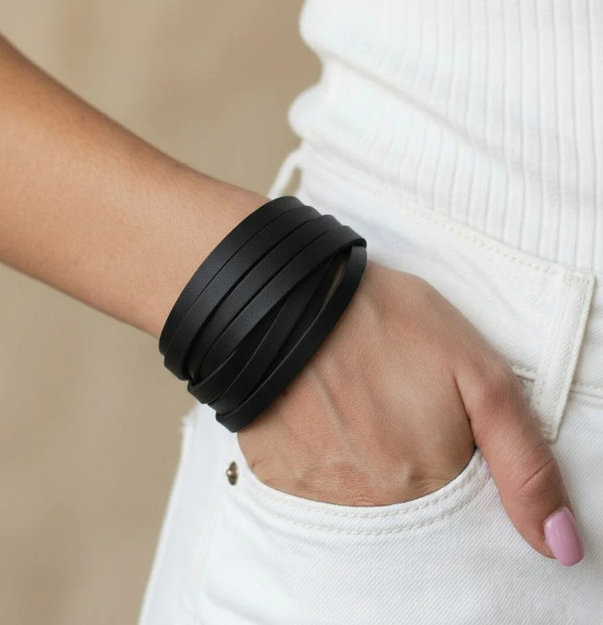 Person wearing a black bracelet on a neutral background