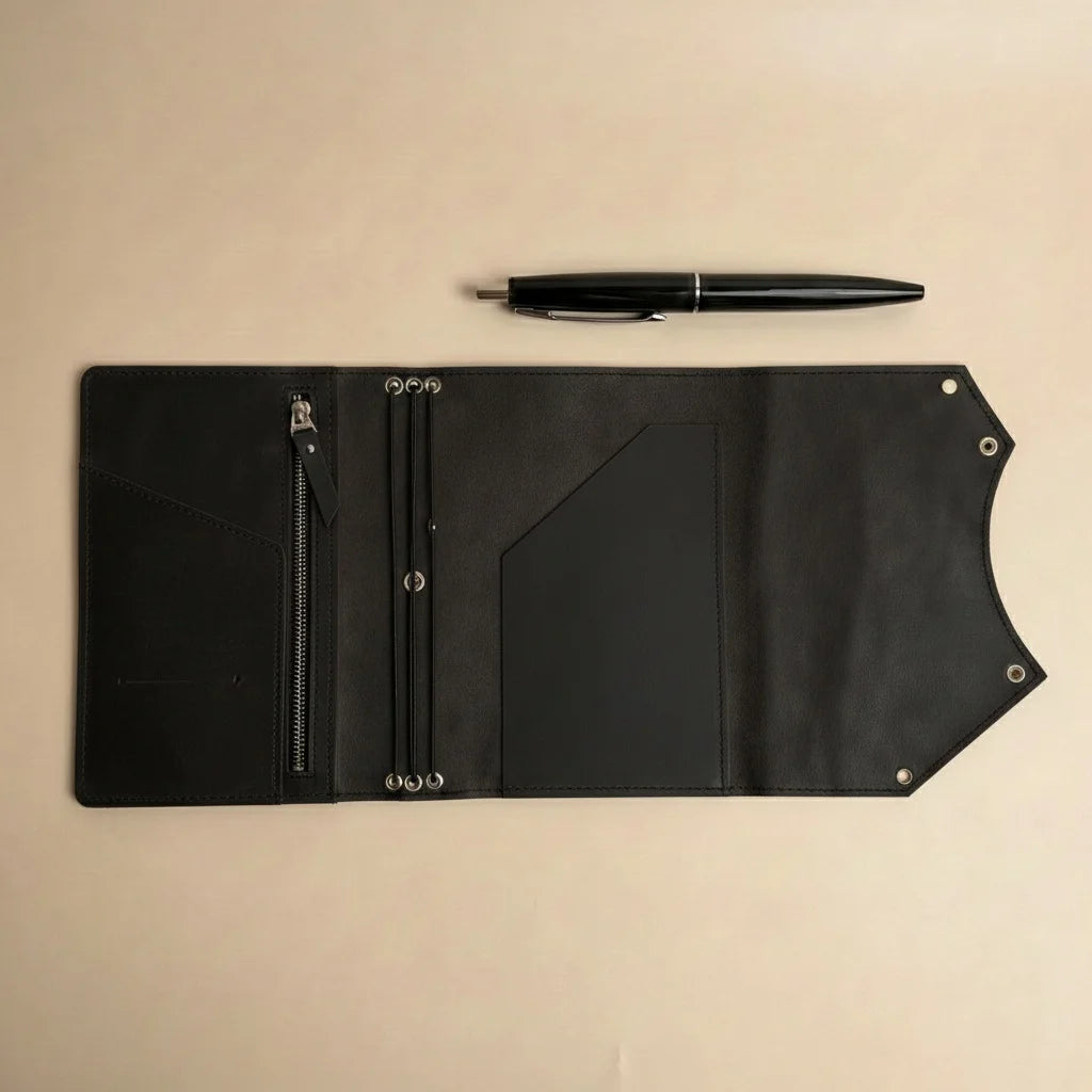 Black leather journal with a pen on a beige background