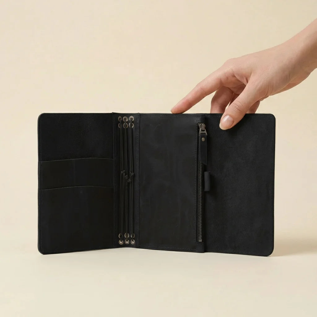 Black leather journal with multiple compartments on a beige background
