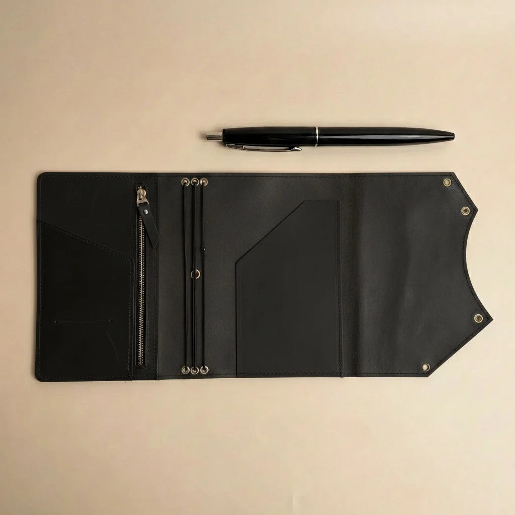 Black leather notebook held by a hand on a beige background
