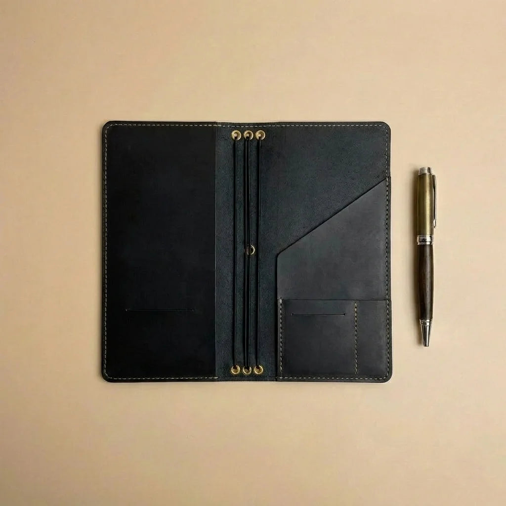 Black leather travel wallet with gold accents on a beige background