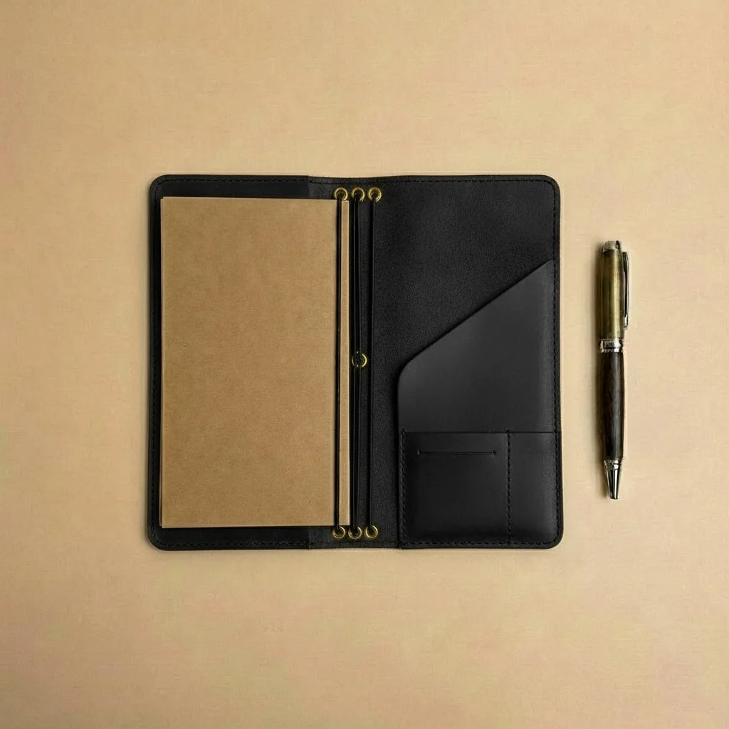 Black leather notebook with a pen on a beige background