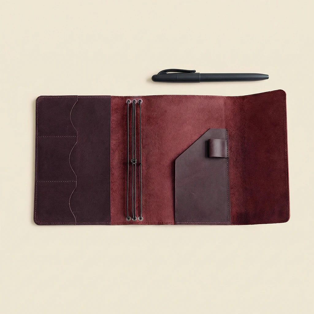 Brown leather journal with pen holder on a beige background