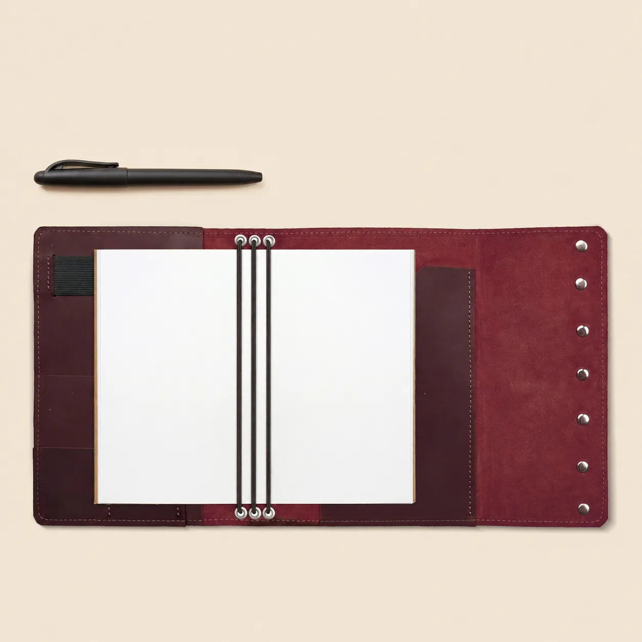 Leather notebook cover designed with storage pockets and integrated pen loop.
