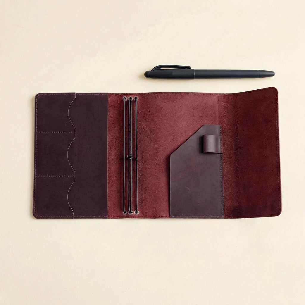 Brown leather journal with pen holder on a beige background