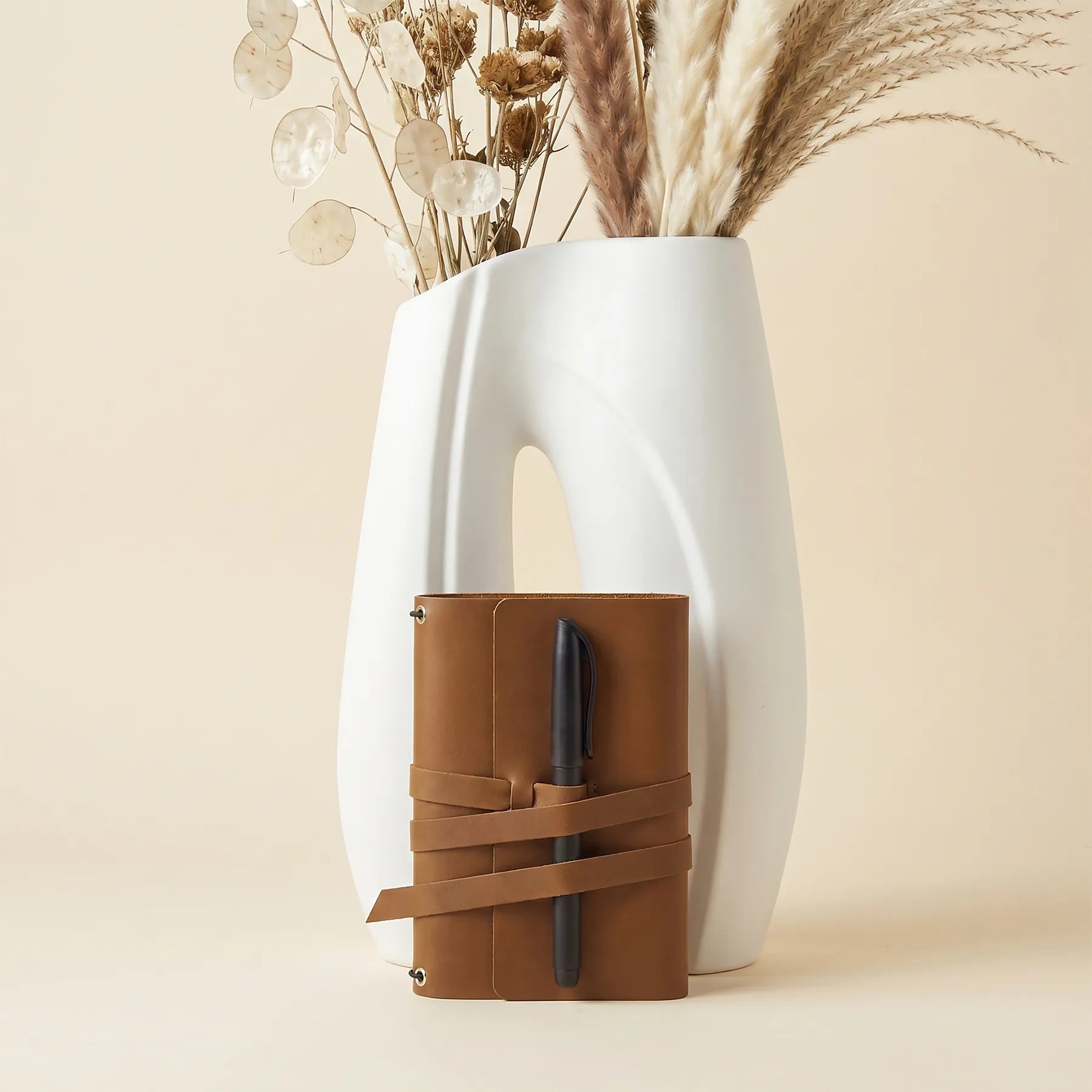 Elegant leather journal cover with integrated pen loops for organized daily note taking.