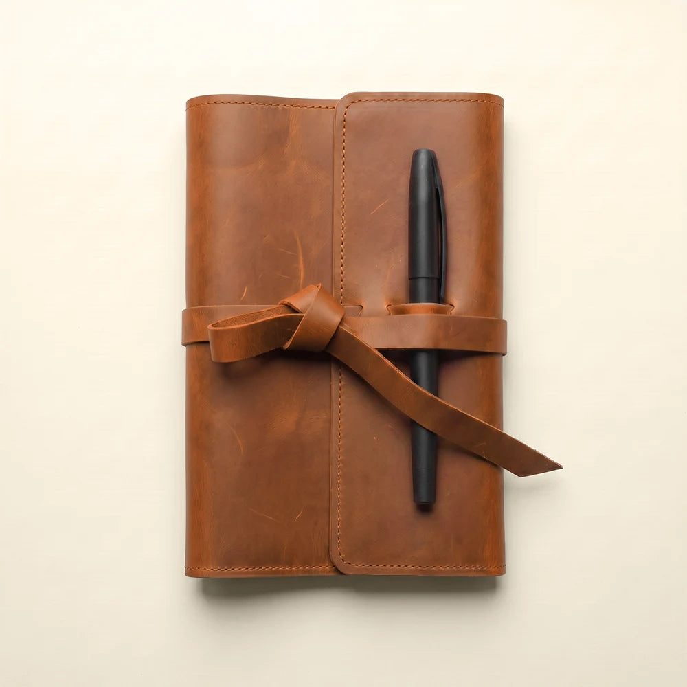 Stylish leather journal cover featuring storage pockets and elastic pen holder.