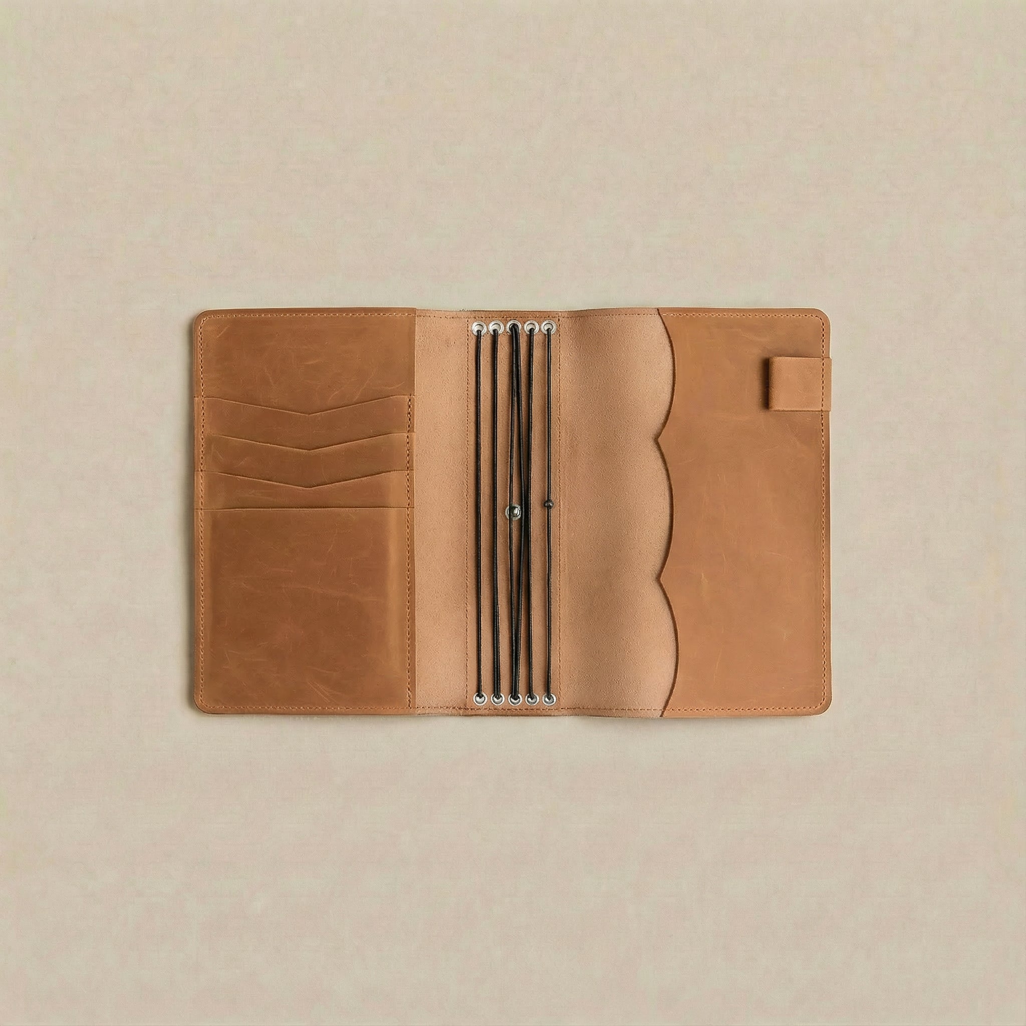 Brown leather notebook held by a hand against a beige background