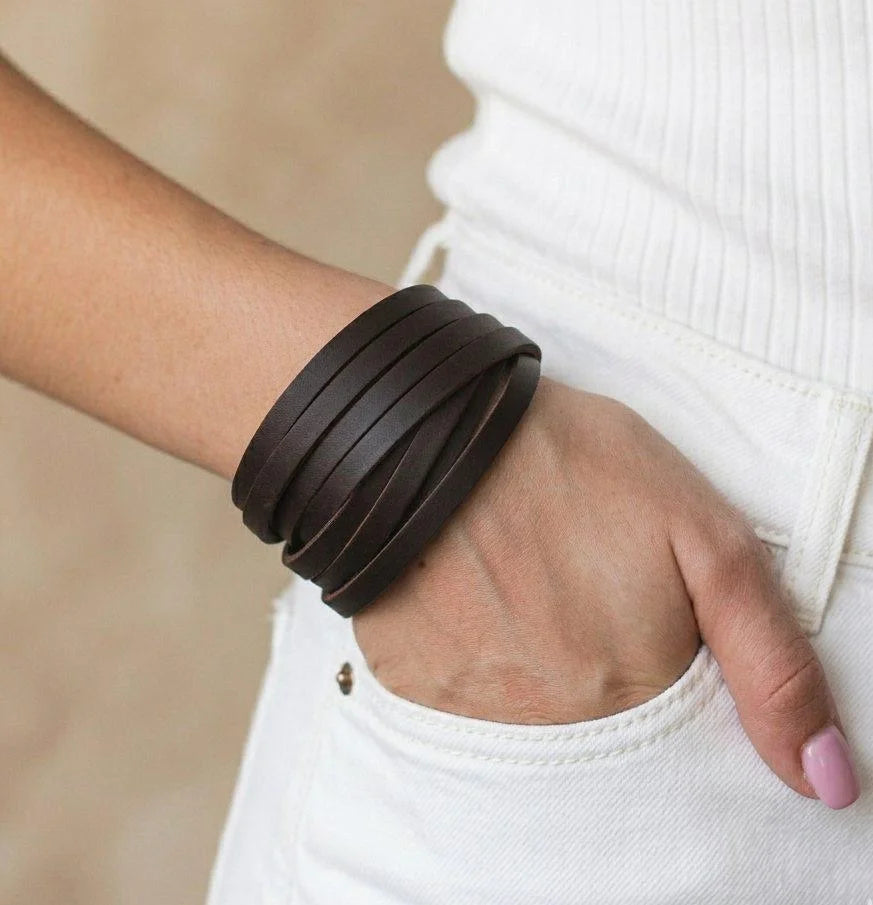 Brown leather bracelet on a wrist with a blurred background
