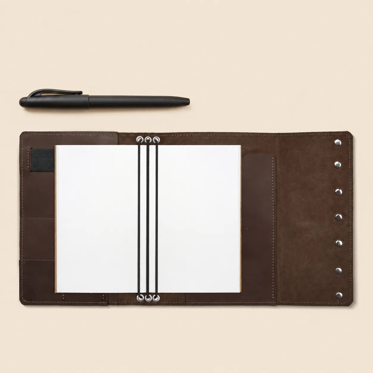 Handmade leather journal cover featuring interior pockets and secure pen holder design.