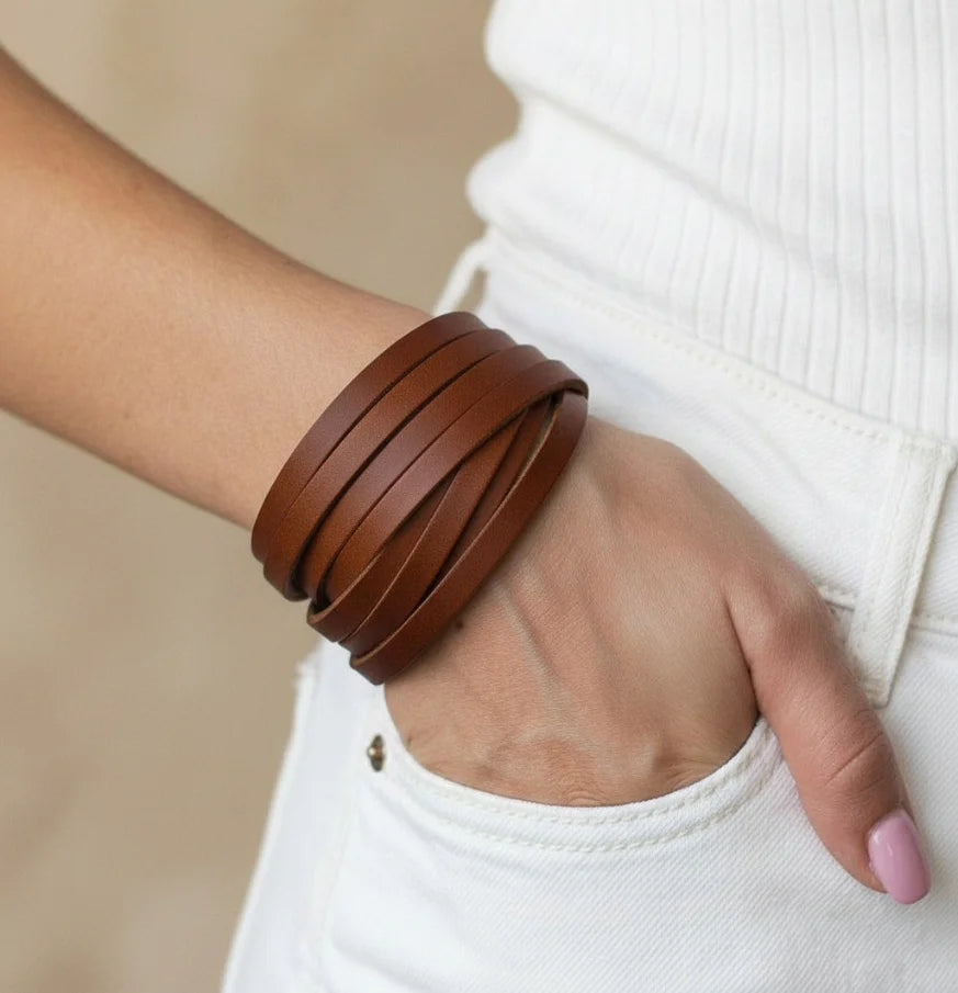 Brown leather bracelet on a wrist with a blurred background