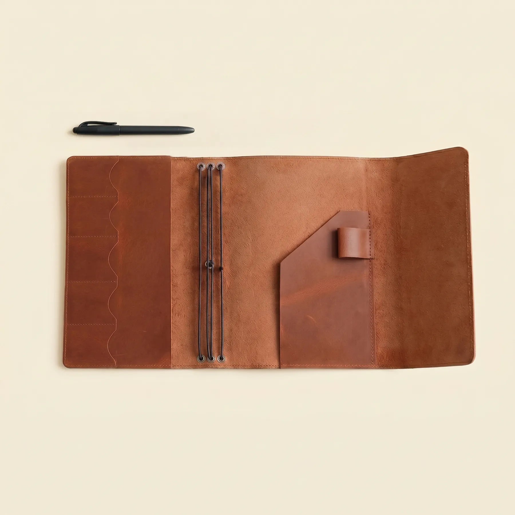 Handmade leather notebook cover with organized interior and pen loop.