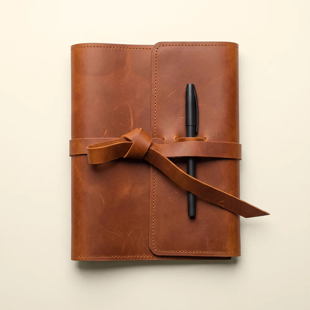 Refillable notebook cover crafted from genuine leather with pockets and pen loop.
