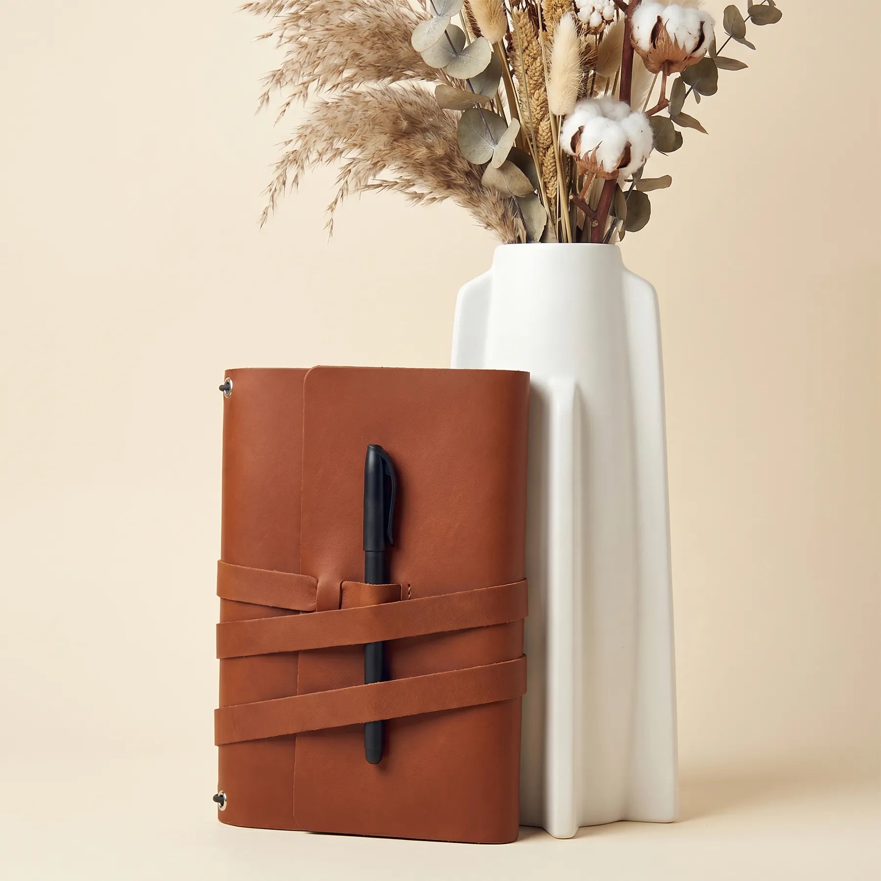 Elegant refillable notebook cover crafted from genuine leather with attached pen loops.
