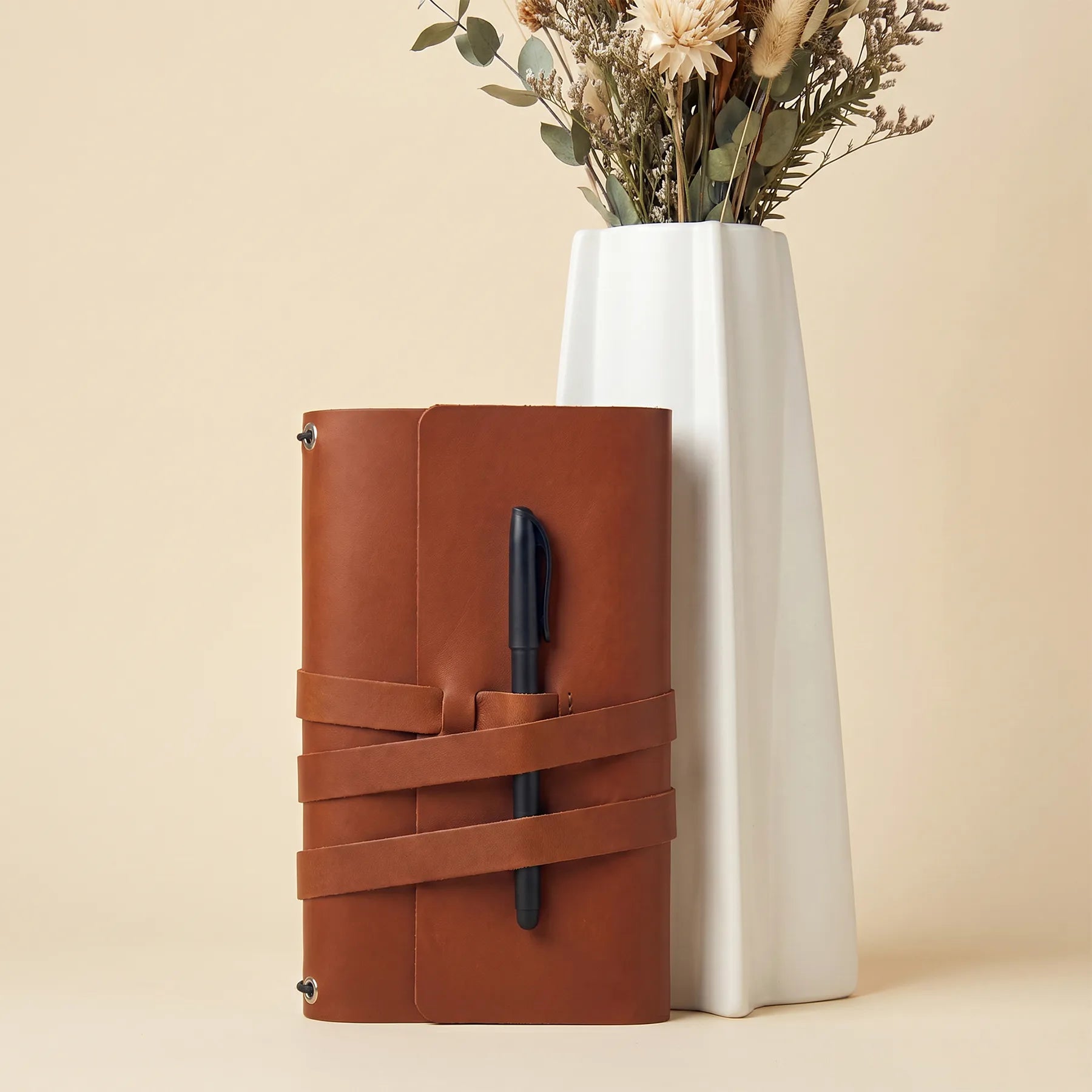 Premium leather notebook cover with functional pen loops and refillable journal compatibility.
