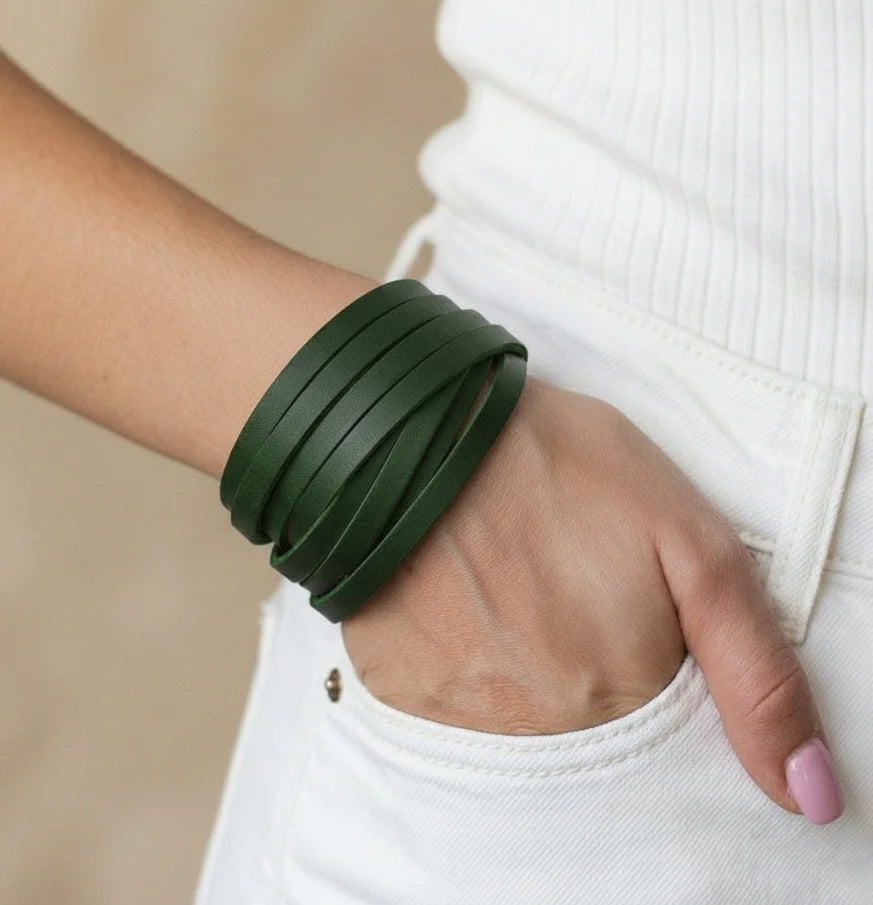 Hand wearing a green bracelet with a blurred background