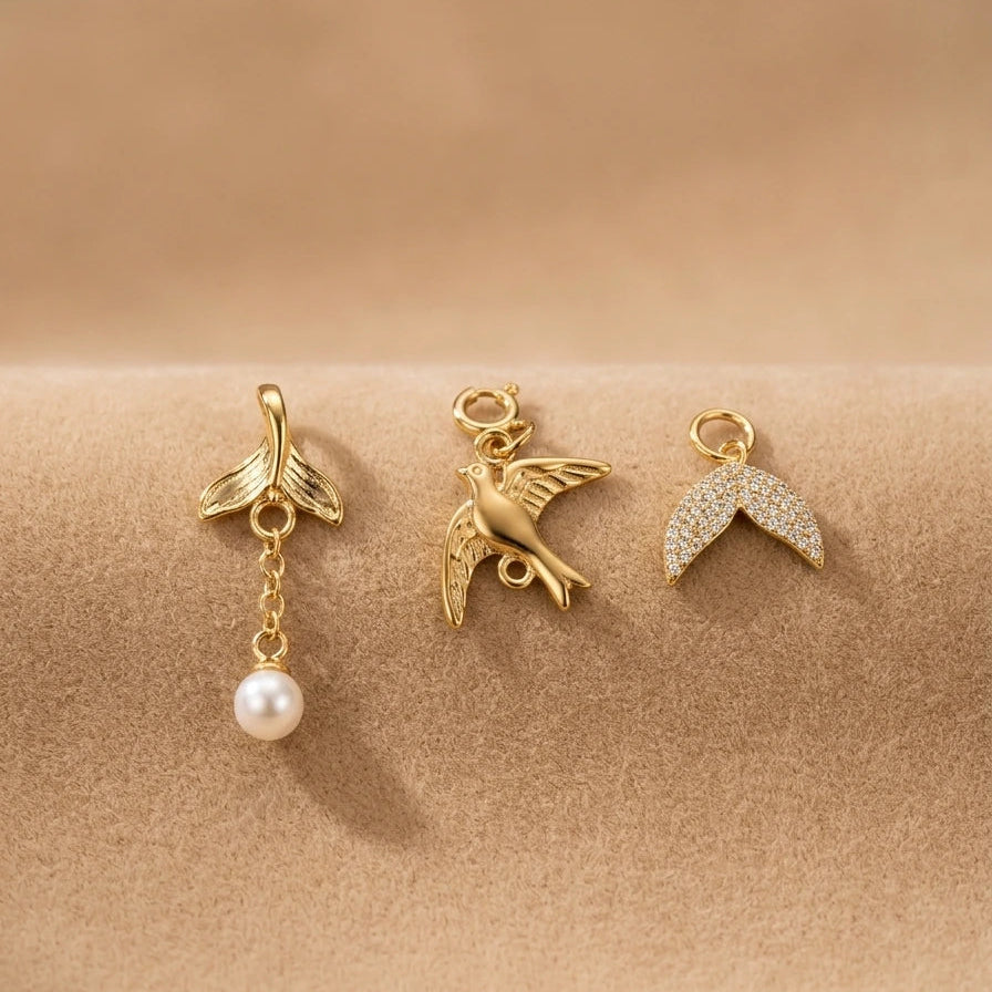 Three gold charms on a beige background
