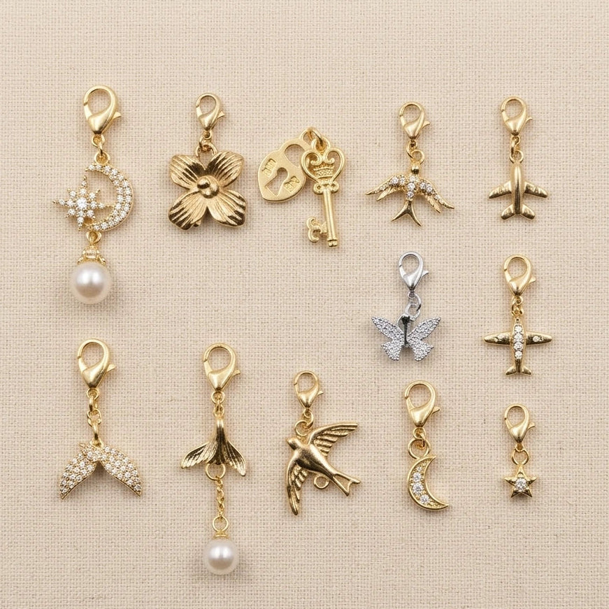 Collection of various gold and silver charms on a beige background